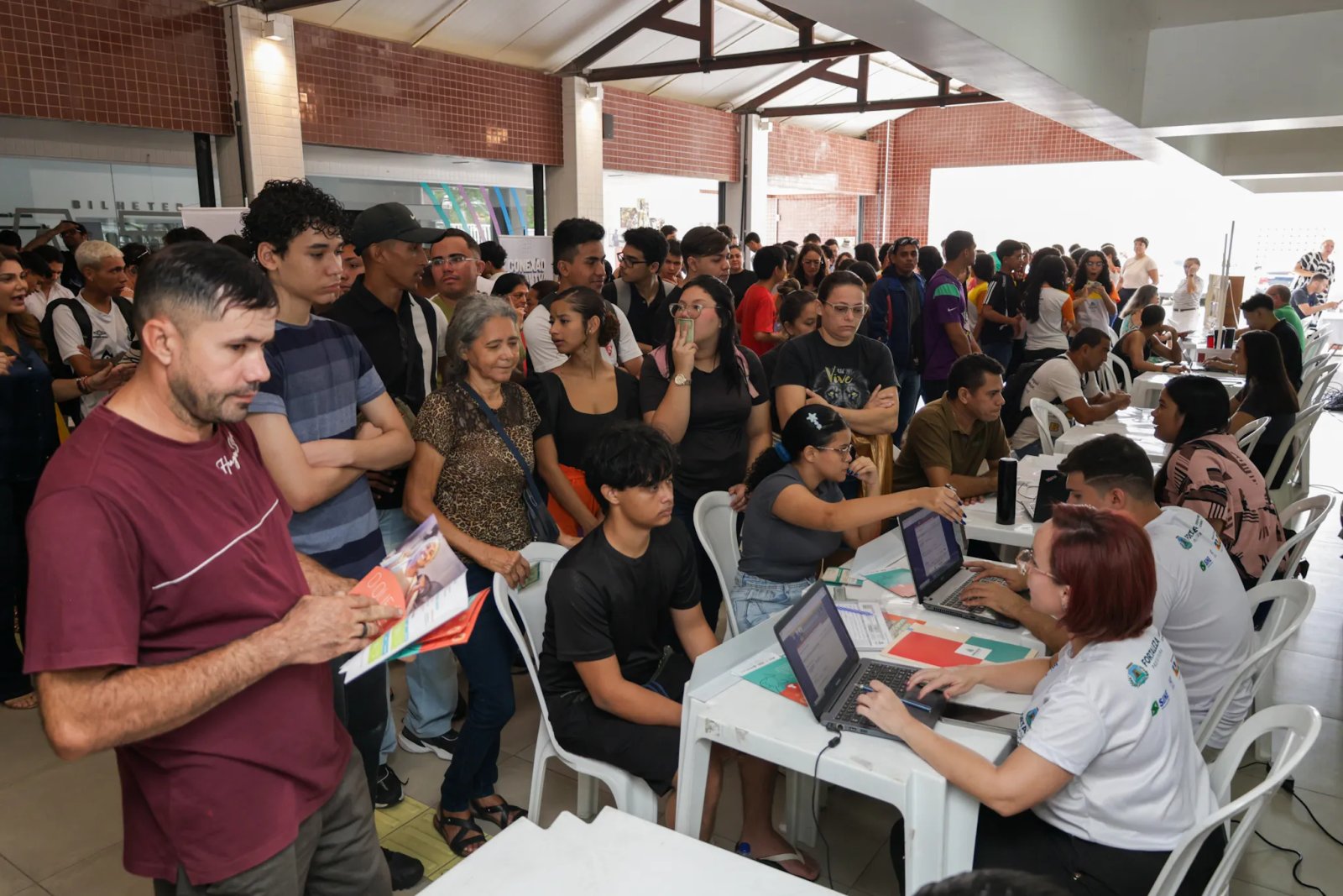 pessoas em pé em fila diante de mesas