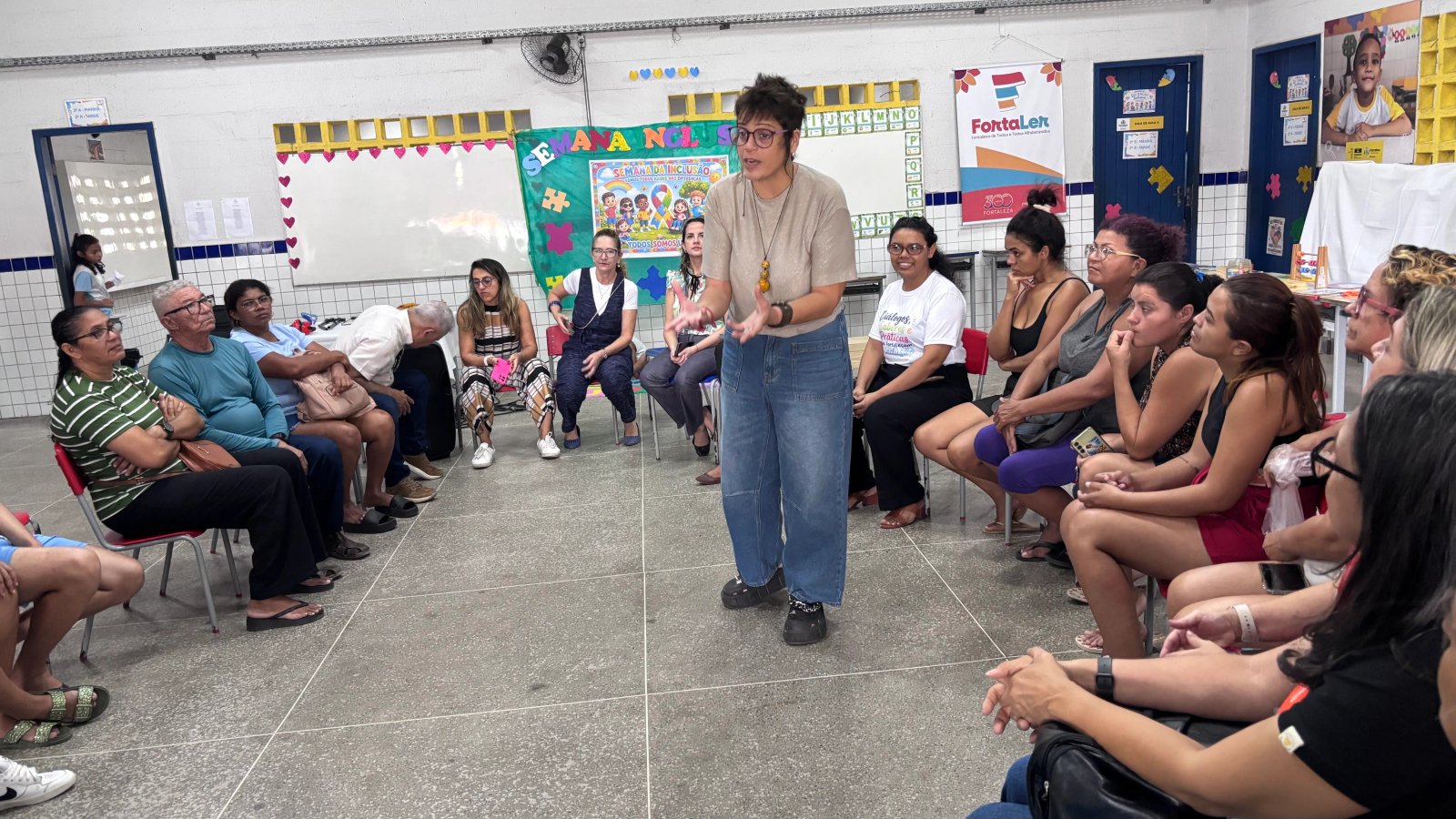 A orientadora Renata Mota facilita uma oficina de parentalidade com familiares em uma sala de aula de escola